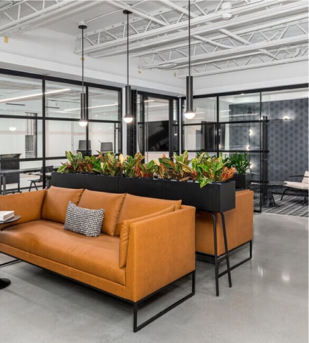 Contemporary coworking space with stylish furniture, glass partitions, and vibrant plants, showcasing Vast Coworking's innovative workspace aligned with Our Framework.