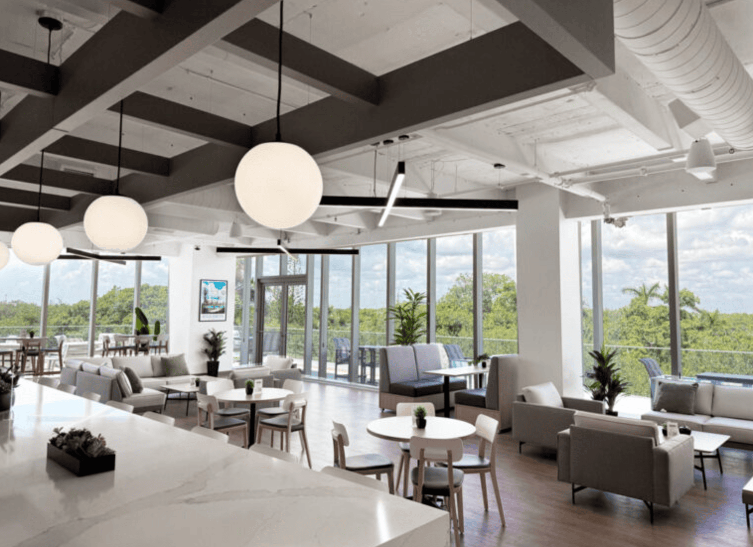 Modern coworking space with large windows, stylish furniture, and contemporary lighting, ideal for productivity and collaboration.
