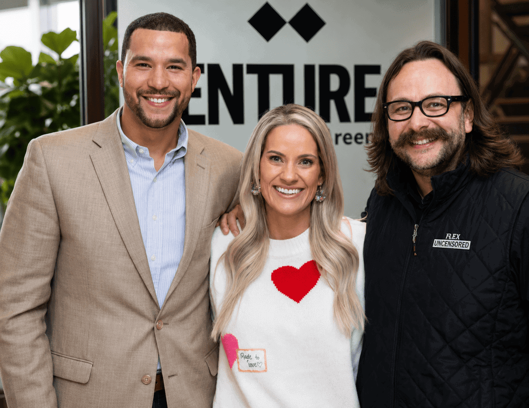 Three diverse professionals smiling at a networking event at Vast Coworking, with a Venture logo in the background.