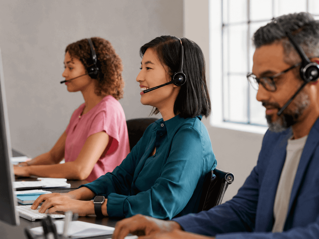 Customer support team wearing headsets working at desks in a modern office space.