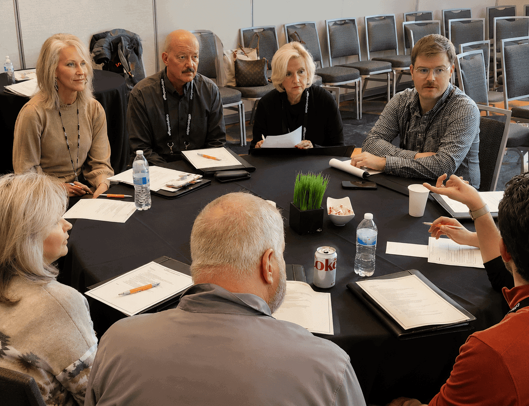 Business meeting with diverse professionals seated around a table in a coworking space.