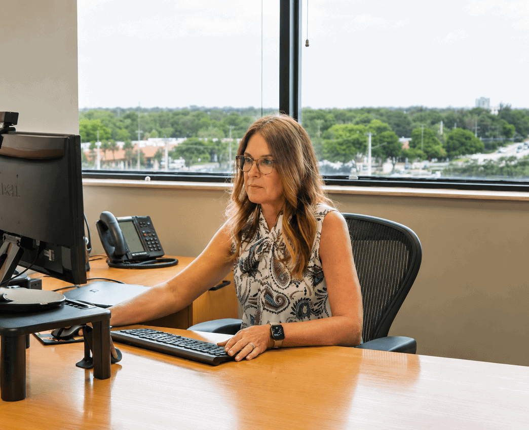 Professional woman working at her desk in a modern coworking space with a large window view.