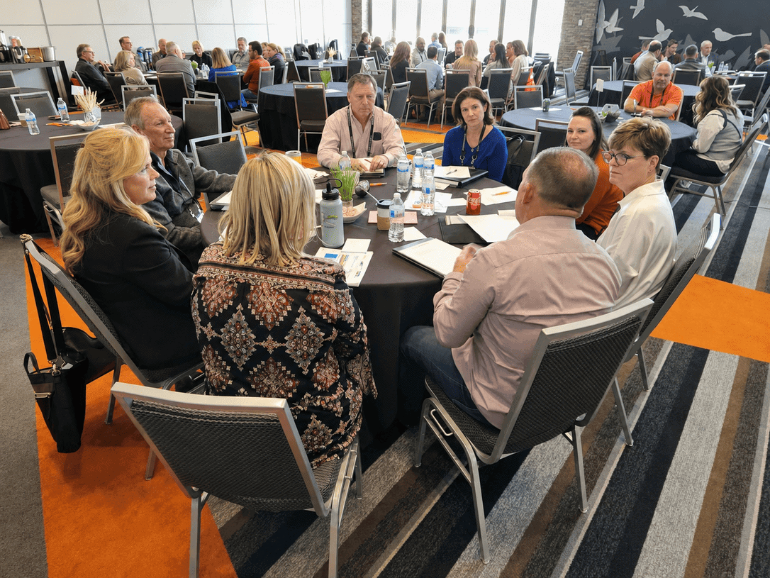 Business professionals engaged in a meeting at Vast Coworking space, with a large group seated around a table in a modern, well-lit conference room.