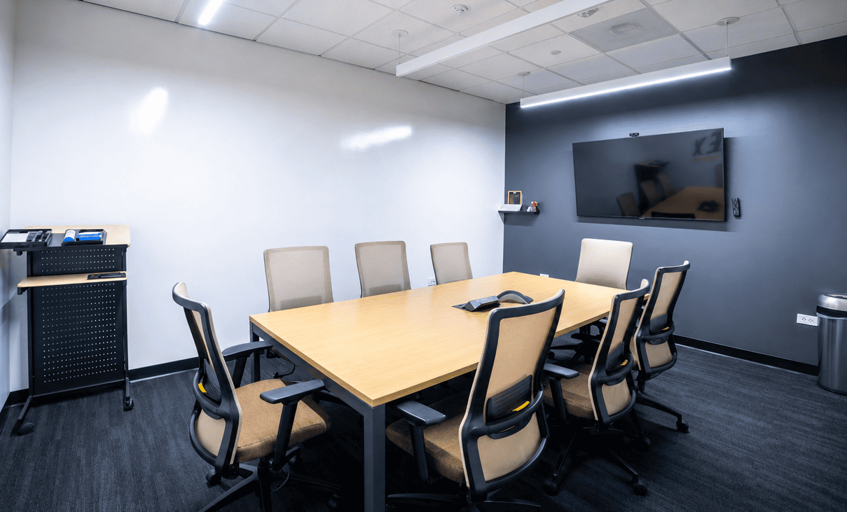 Modern conference room at Vast Coworking with a large wooden table and eight ergonomic chairs.