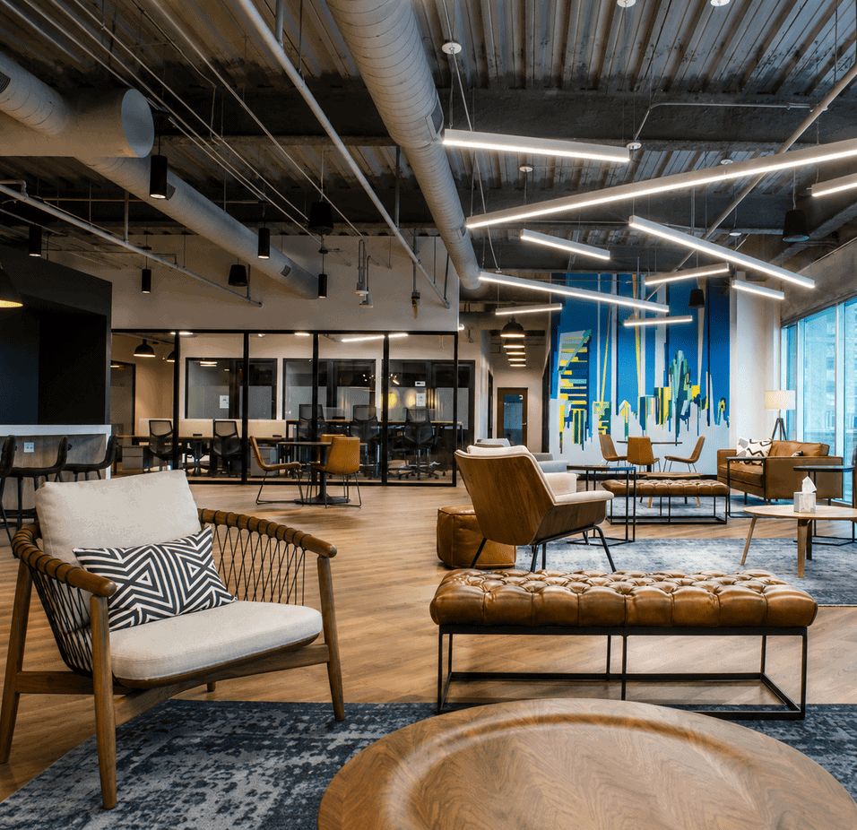 Modern coworking space with stylish furniture, artistic wall decor, and contemporary lighting in a vibrant office environment.